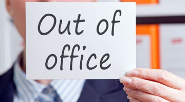 La personne tient une pancarte avec le texte Hors du bureau en grandes lettres claires.