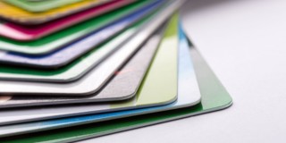 Un empilement de cartes métalliques colorées dans différentes teintes, avec un accent sur la carte verte située en haut.