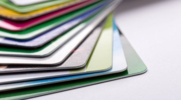 Un empilement de cartes métalliques colorées dans différentes teintes, avec un accent sur la carte verte située en haut.