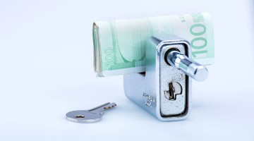 Un mécanisme de fermeture avec une clé et une lettre roulée de cent euros, symbolisant la sécurité de l'argent.
