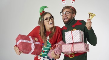 Deux personnes en tenue de fête tiennent des cadeaux de Noël colorés, entourées d'une ambiance festive.
