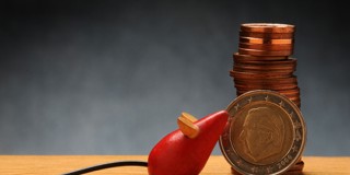 Une boîte électrique rouge avec une prise à côté d'une pile de pièces de monnaie et d'une pièce en euro symbolise la connexion entre l'énergie et l'argent.