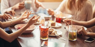 Un groupe d'amis savoure un dîner informel avec plusieurs plats et boissons sur la table.