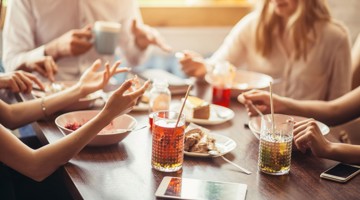 Un groupe d'amis savoure un dîner informel avec plusieurs plats et boissons sur la table.