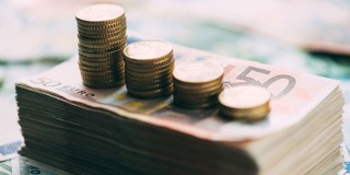 Des piles de billets en euros accompagnées de pièces de monnaie croissantes, symbolisant la croissance de l'argent ou des investissements.