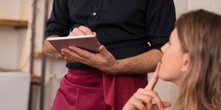 Un serveur avec une tablette discute des choix de menu avec un client.