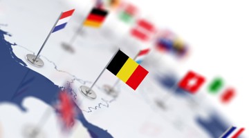 België gemarkeerd op een wereldkaart met vlaggen van andere landen op de achtergrond.