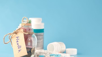 Bocaux en verre contenant de l'argent, étiquetés Santé, entourés de médicaments et de pilules sur un fond bleu.