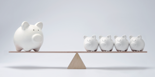 Een grote witte spaarpot staat aan de linkerkant van een houten balans, terwijl vier kleinere witte spaarpotten aan de rechterkant staan.