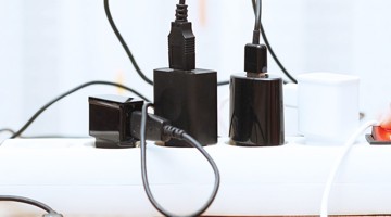 Différentes chargeurs et prises connectés à une multiprise blanche.