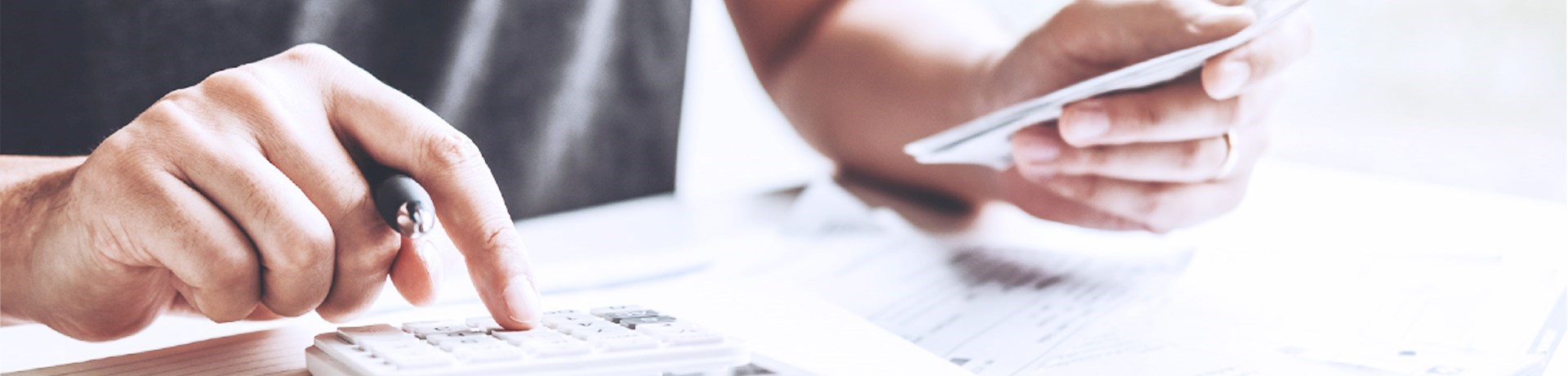 Hand die een rekenmachine gebruikt, terwijl de andere hand een creditcard vasthoudt.