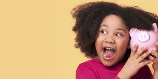 Fille aux cheveux bouclés tient un cochon tirelire rose devant son visage, sur un fond jaune.