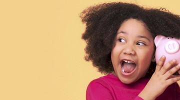 Fille aux cheveux bouclés tient un cochon tirelire rose devant son visage, sur un fond jaune.