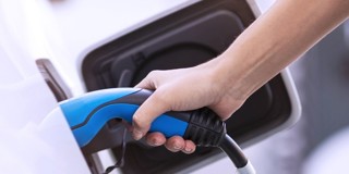 Hand die een oplaadkabel voor een elektrische auto aansluit.