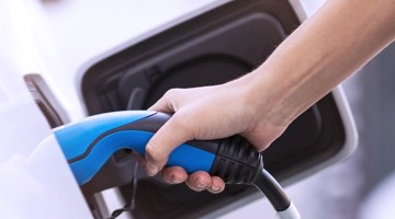 Hand die een oplaadkabel voor een elektrische auto aansluit.