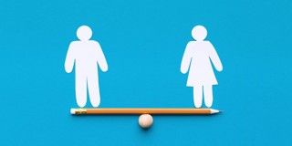 Papieren figuren van een man en een vrouw die in balans staan op een potlood, als symbool voor gendergelijkheid.