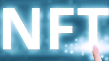 Lettres blanches NFT sur un fond bleuâtre, avec un doigt pointant vers le T.