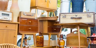 Een kleurrijke selectie van vintage meubels en accessoires, zoals kisten, kasten en flessen, op een tweedehandsmarkt.