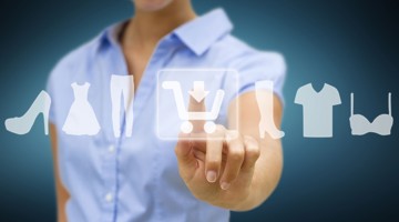 Een vrouw in een blauw shirt tikt op een digitale interface met pictogrammen van kleding en schoenen, gericht op online winkelen.