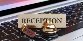 Gouden receptiebeld en bord met het woord 'RECEPTIE' op een laptoptoetsenbord.
