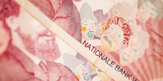 Close-up van een bankbiljet met de tekst NATIONALE BANK en abstracte gezichten in verschillende kleuren.