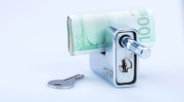 Een grijze geldkluis met een opgerold €100-biljet en een sleutel ernaast.