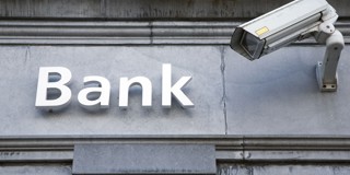 Een camera richt zich op het woord 'Bank' dat op een grijze muur is geschilderd.