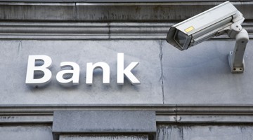 Een camera richt zich op het woord 'Bank' dat op een grijze muur is geschilderd.