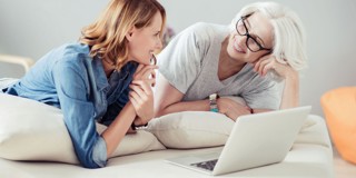 Twee personen zitten op een bank en kijken samen naar een laptop in een sfeervolle woonkamer.