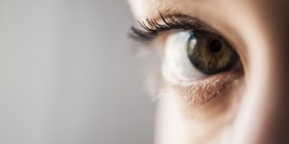 Nabijbeeld van een oog met een heldere groene iris en lange wimpers, volledig gericht op de pupil.