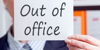 Hand houdt een bordje met de tekst 'Niet op kantoor'.