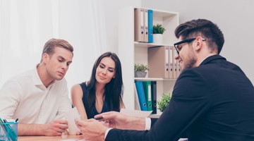 Een groep mensen in een vergaderruimte bespreekt documenten en notities die op tafel liggen.