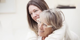 Een jonge vrouw omarmt een oudere vrouw in een warme en gezellige setting.