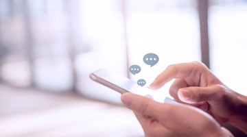 Een persoon gebruikt een smartphone met spraak- of chatballonnen die op het scherm verschijnen.