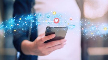 Une femme tient un smartphone avec un réseau d'icônes de médias sociaux et des cœurs flottant autour.