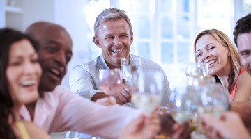 Vrienden proosten met glazen vol drinken aan een feestelijke tafel, omringd door een vrolijke en gezellige sfeer.