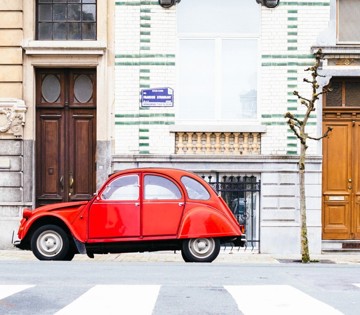 Rode vintage auto geparkeerd op een straat met historische gebouwen.