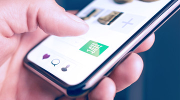 Een hand tikt op een smartphone met een groen winkelwagentje-icoon, omringd door verschillende andere pictogrammen.