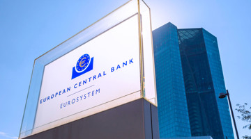 Logo de la Banque Centrale Européenne sur une plaque translucide devant un immeuble de bureaux moderne.