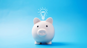 Witte spaarpot met een gloeilamp erboven, symbool voor financiële ideeën of plannen.