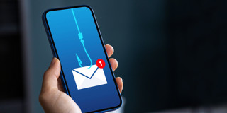 Une main tient un smartphone affichant un crochet de pêche et une notification d'un e-mail reçu à l'écran.