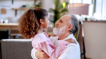 Un parent jouant avec un enfant, tous deux souriants dans un environnement chaleureux et familier.