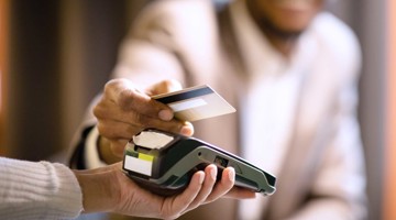Des clients paient par carte bancaire à un terminal de paiement dans un magasin.