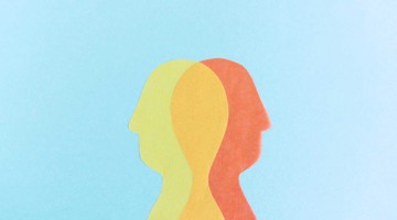 Silhouettes de deux visages en jaune et orange sur un fond bleu, symbolisant la communication et la connexion.