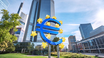 Sculpture d'un symbole Euro bleu entourée d'étoiles dorées devant le bâtiment de la BCE à Francfort, avec des gratte-ciel modernes en arrière-plan.