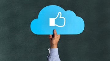 Een hand houdt een blauw wolkenicoon vast met een wit duim omhoog symbool, wat positieve feedback of goedkeuring suggereert.