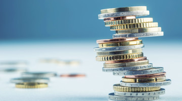 Stapels munten van verschillende waarden, die sparen of investeren symboliseren.