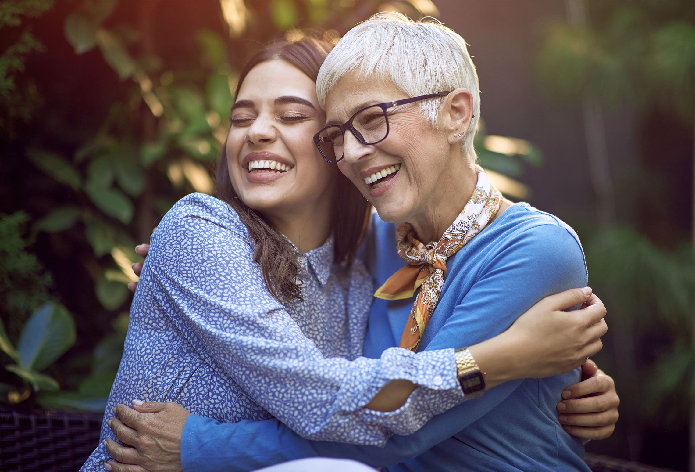 Twee mensen omhelzen elkaar in een groene tuin, stralend in een warme en gezellige sfeer.