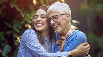 Twee mensen omhelzen elkaar in een groene tuin, stralend in een warme en gezellige sfeer.