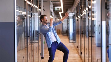 Man danst blij in een moderne kantoorruimte met glazen wanden.